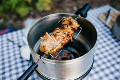 Picnic table with Cobb Cooker and Rotisserie cooking chicken thighs