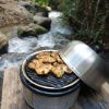 chicken cooking on Cobb griddle with rocky water feature back drop