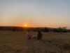 two people sitting on grass cooking on the Cobb Premier Air portable charcoal cooker